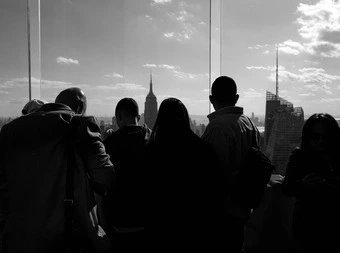Black and white group of people looking at New York skyscape from the Top of the Rock